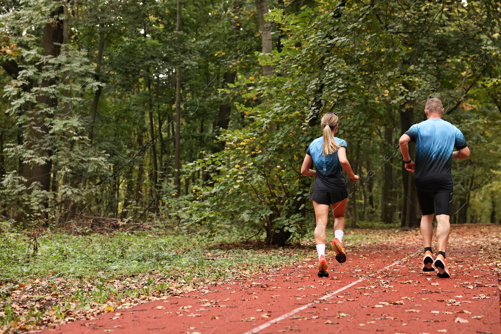 Photo of Athletic man and woman running in park, back view. Space for text