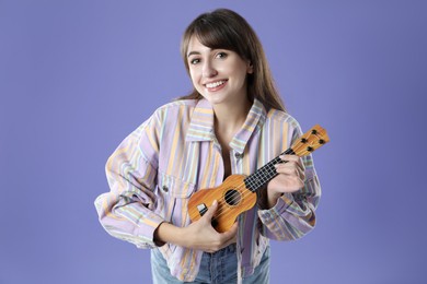 Photo of Happy woman playing ukulele on purple background