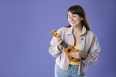 Happy woman playing ukulele on purple background, space for text