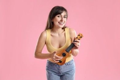 Photo of Happy woman playing ukulele on pink background