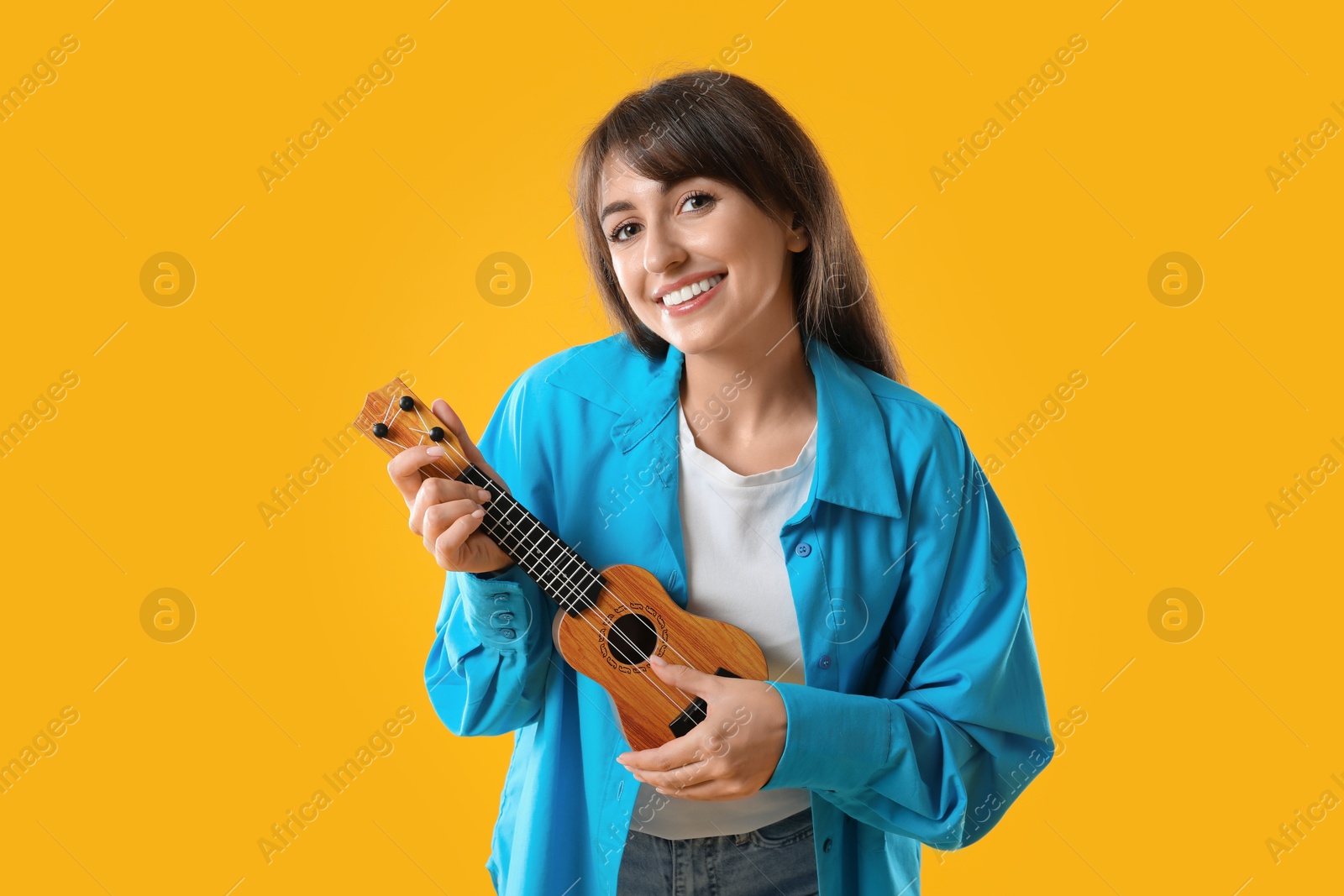 Photo of Happy woman playing ukulele on orange background