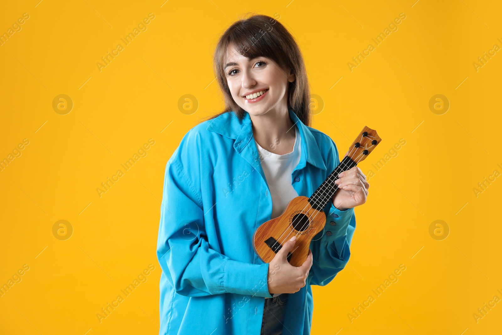 Photo of Happy woman playing ukulele on orange background