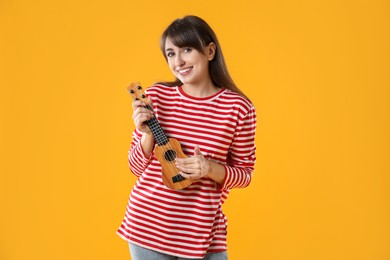 Photo of Happy woman playing ukulele on orange background