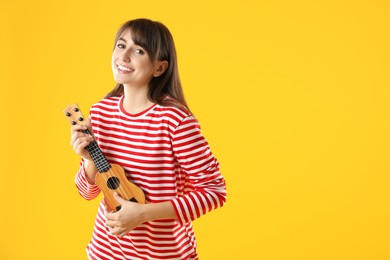 Happy woman playing ukulele on orange background, space for text