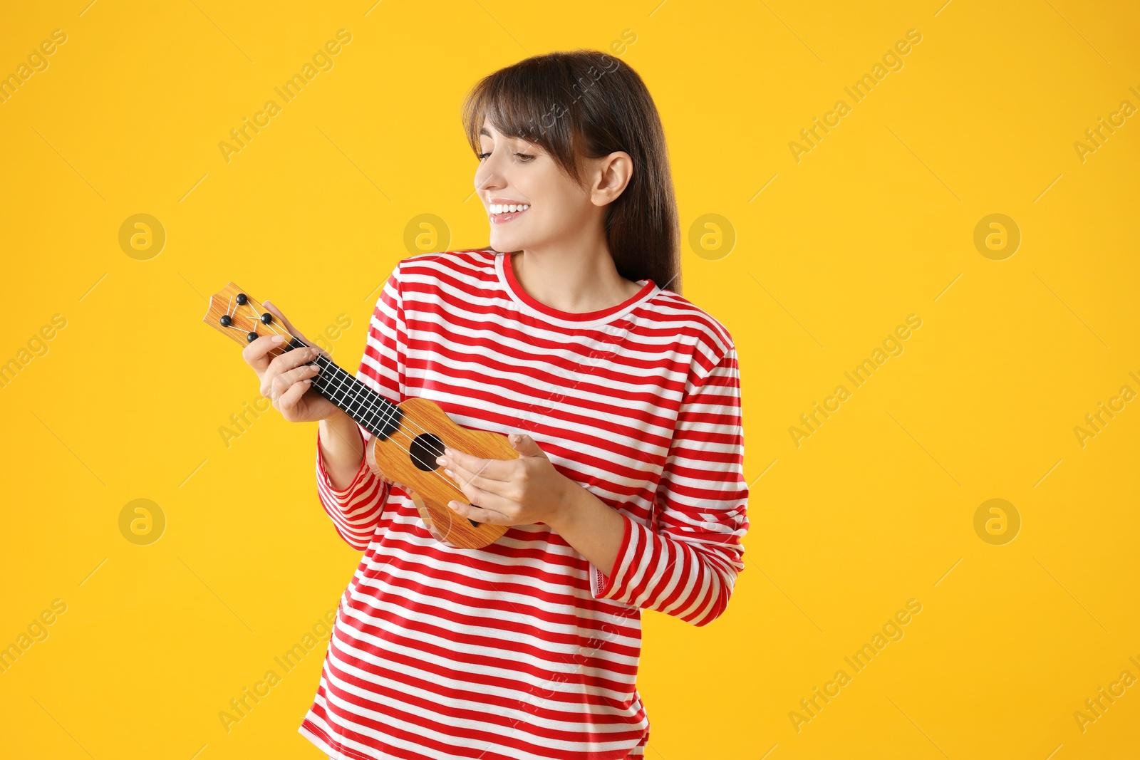 Photo of Happy woman playing ukulele on orange background