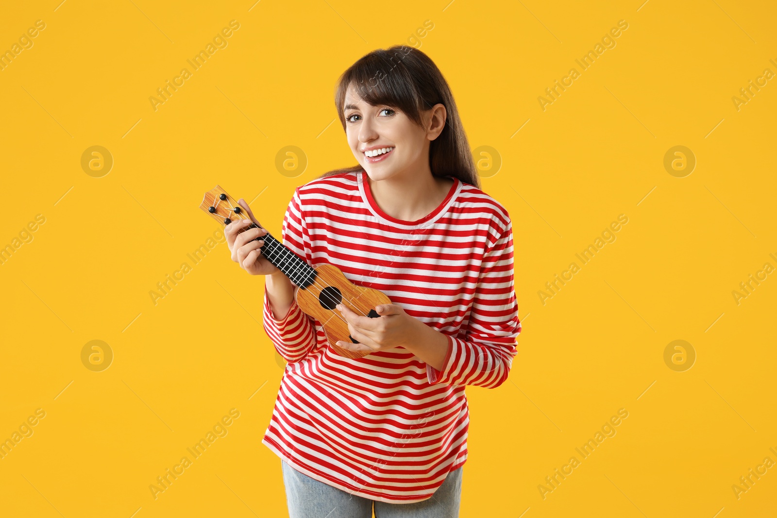 Photo of Happy woman playing ukulele on orange background