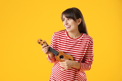 Photo of Happy woman playing ukulele on orange background