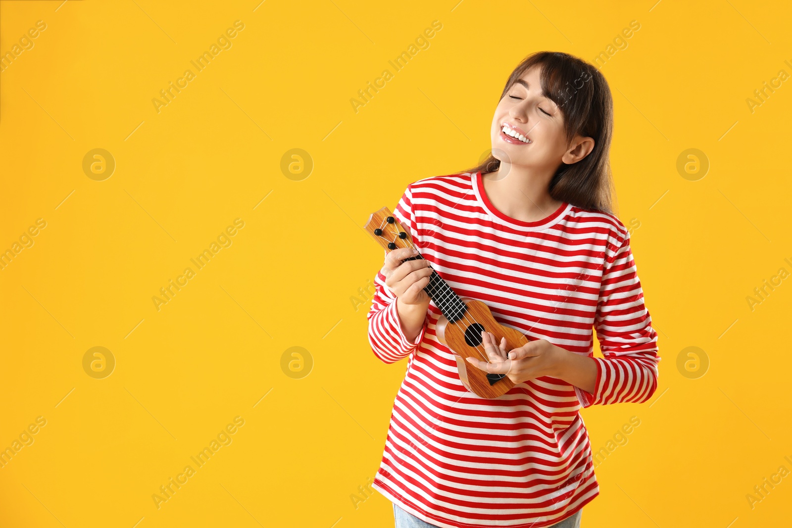 Photo of Happy woman playing ukulele on orange background, space for text