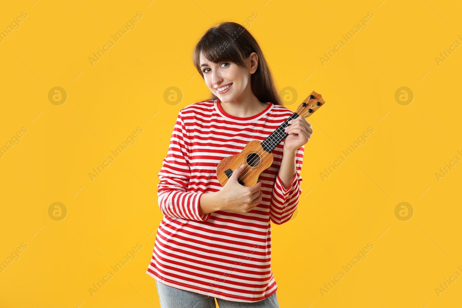 Photo of Happy woman playing ukulele on orange background