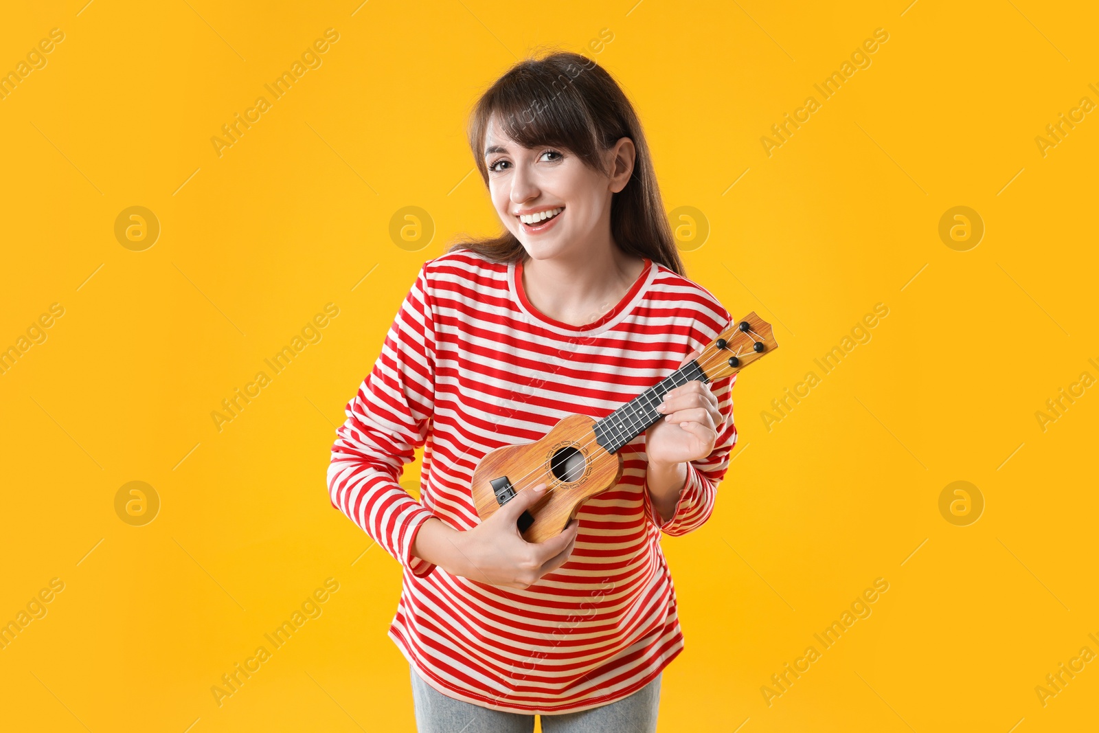 Photo of Happy woman playing ukulele on orange background