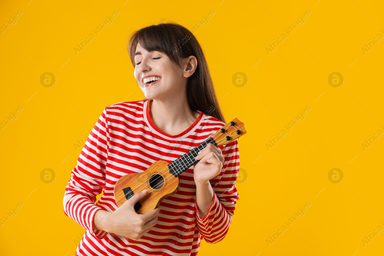 Photo of Happy woman playing ukulele on orange background, space for text