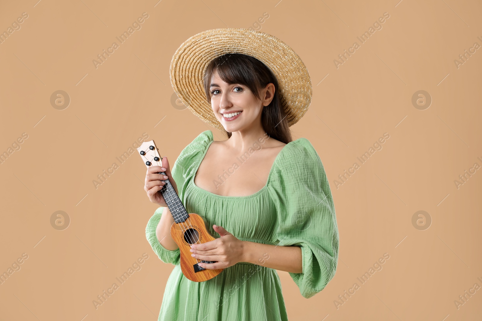 Photo of Happy woman playing ukulele on beige background