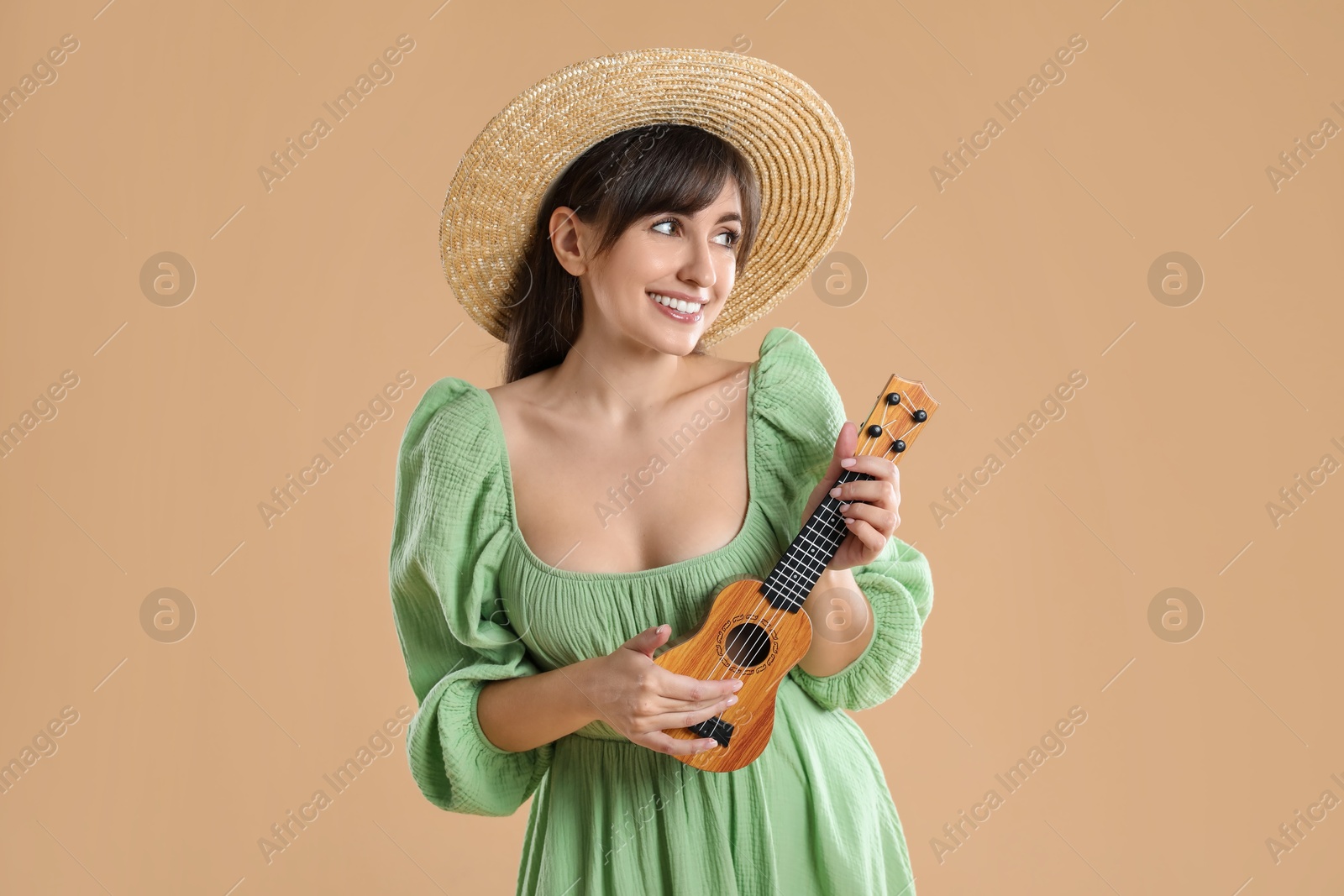 Photo of Happy woman playing ukulele on beige background