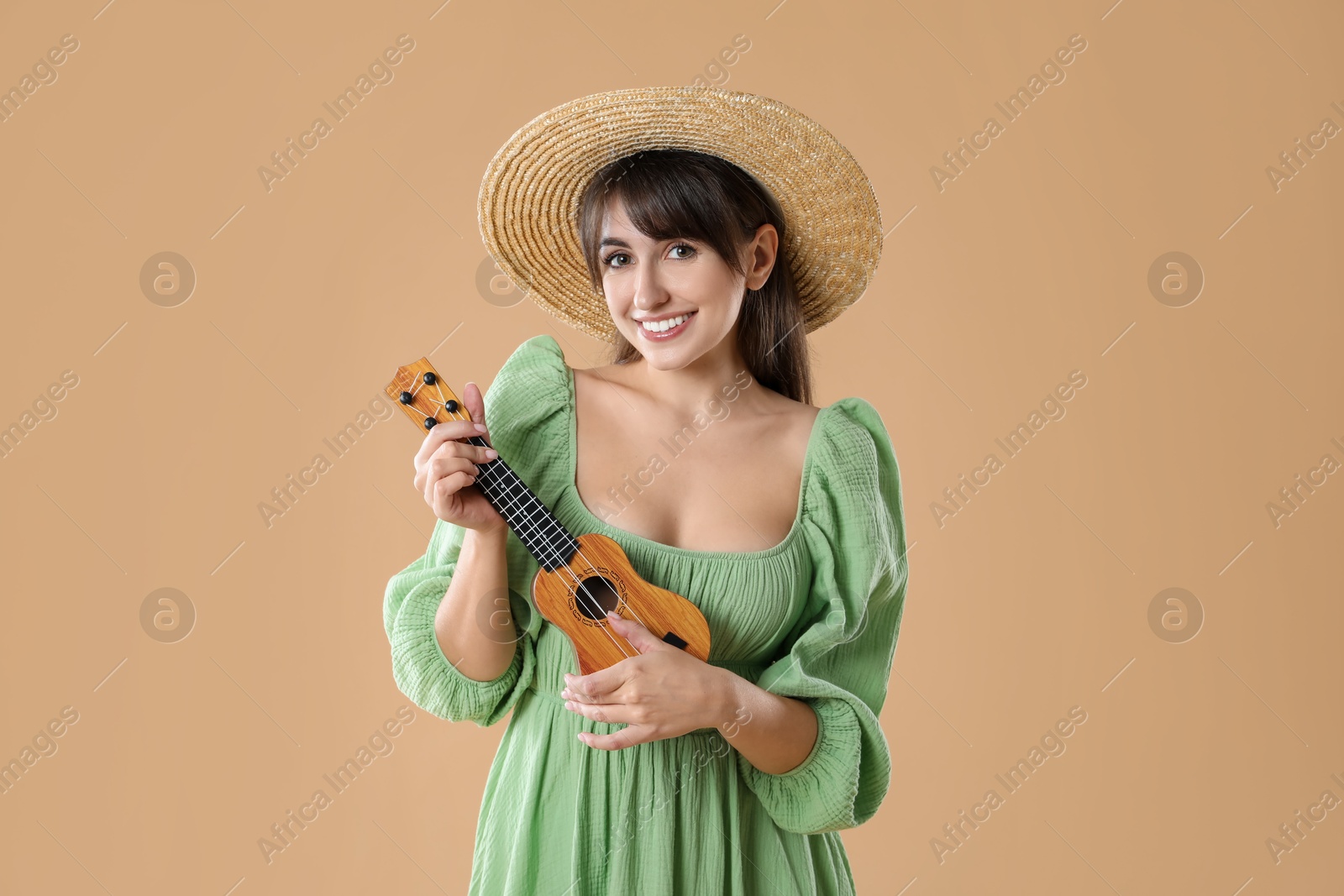 Photo of Happy woman playing ukulele on beige background