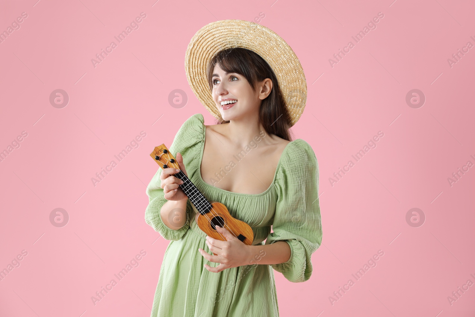 Photo of Happy woman playing ukulele on pink background