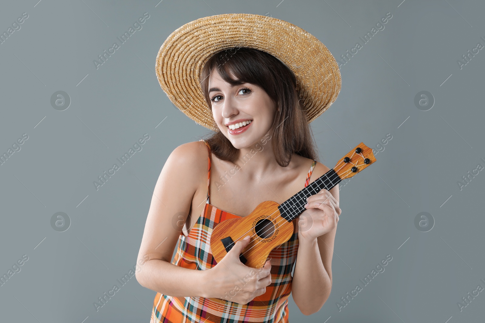 Photo of Happy woman playing ukulele on grey background