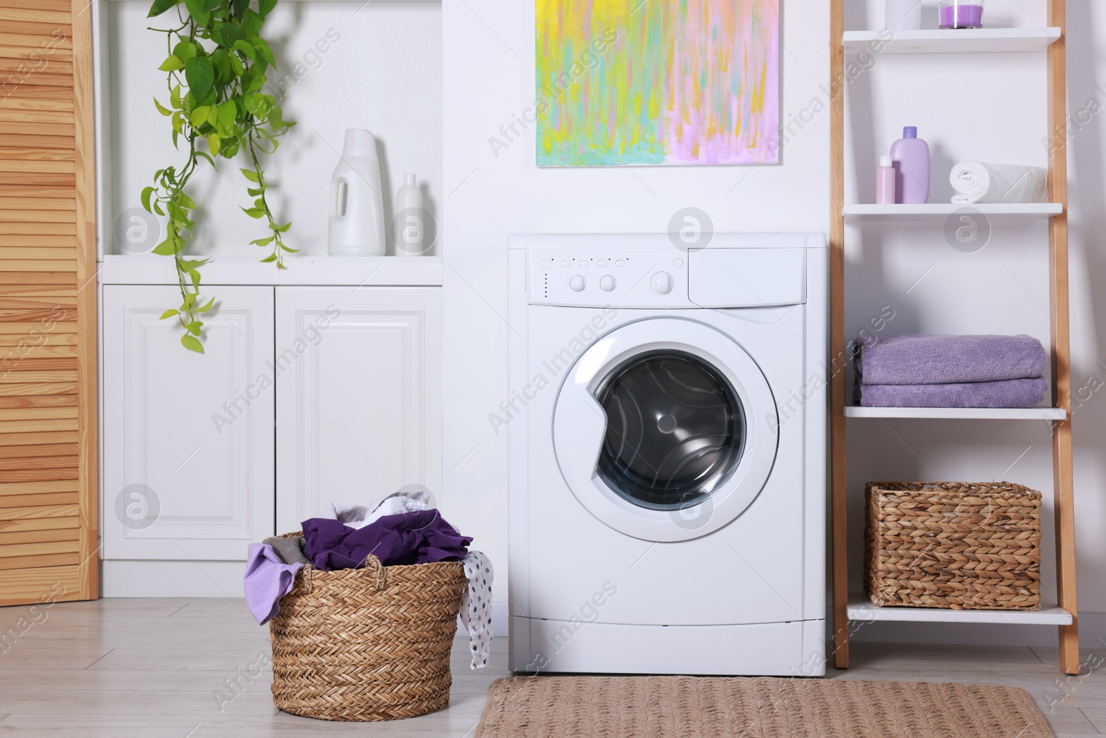 Photo of Washing machine, detergents, clean towels and basket with laundry in room