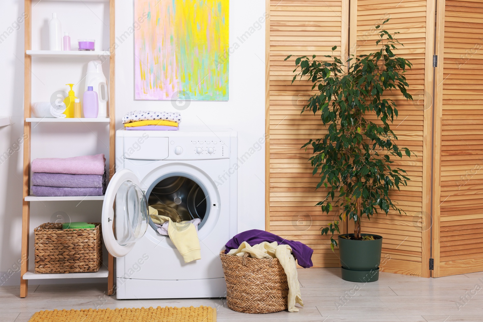 Photo of Washing machine, detergents, clean towels and basket with laundry in room