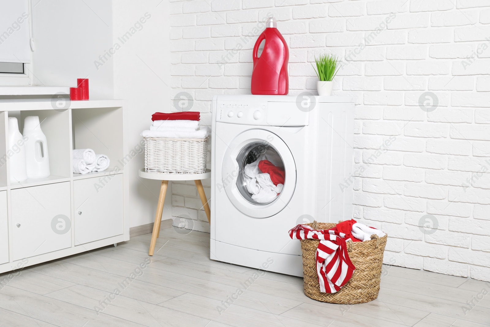 Photo of Washing machine, detergents and basket with laundry in room