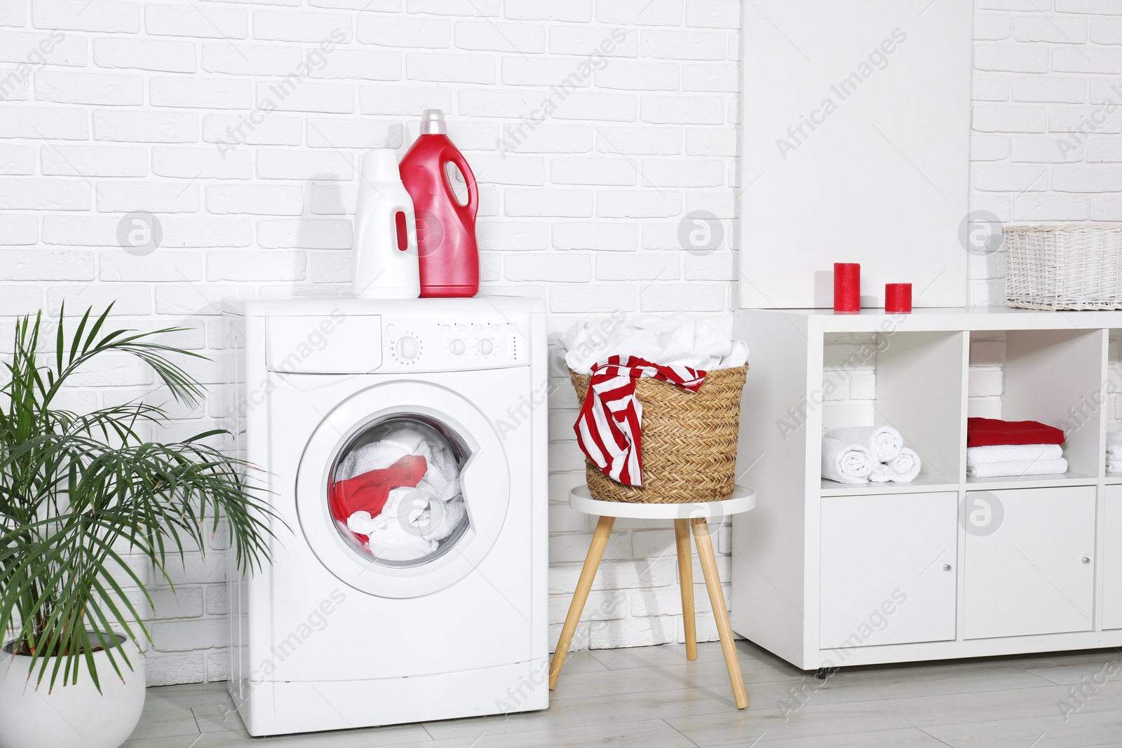 Photo of Washing machine, detergents and basket with laundry in room