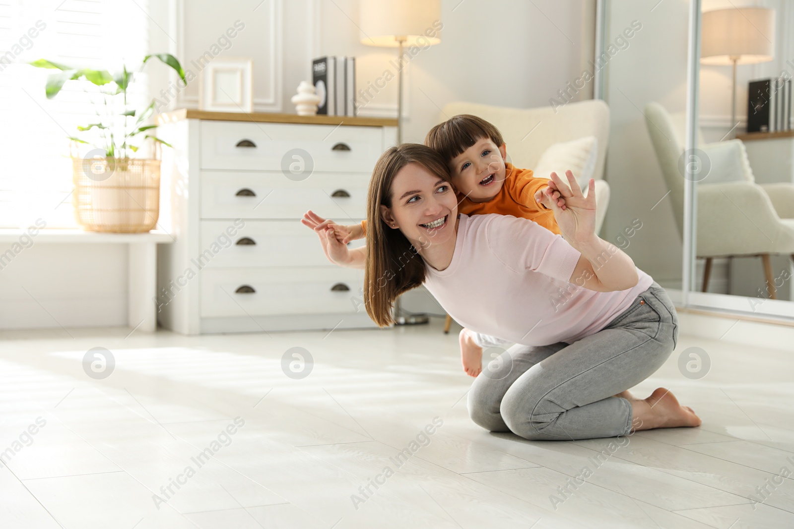 Photo of Happy mother playing with her little son at home. Space for text