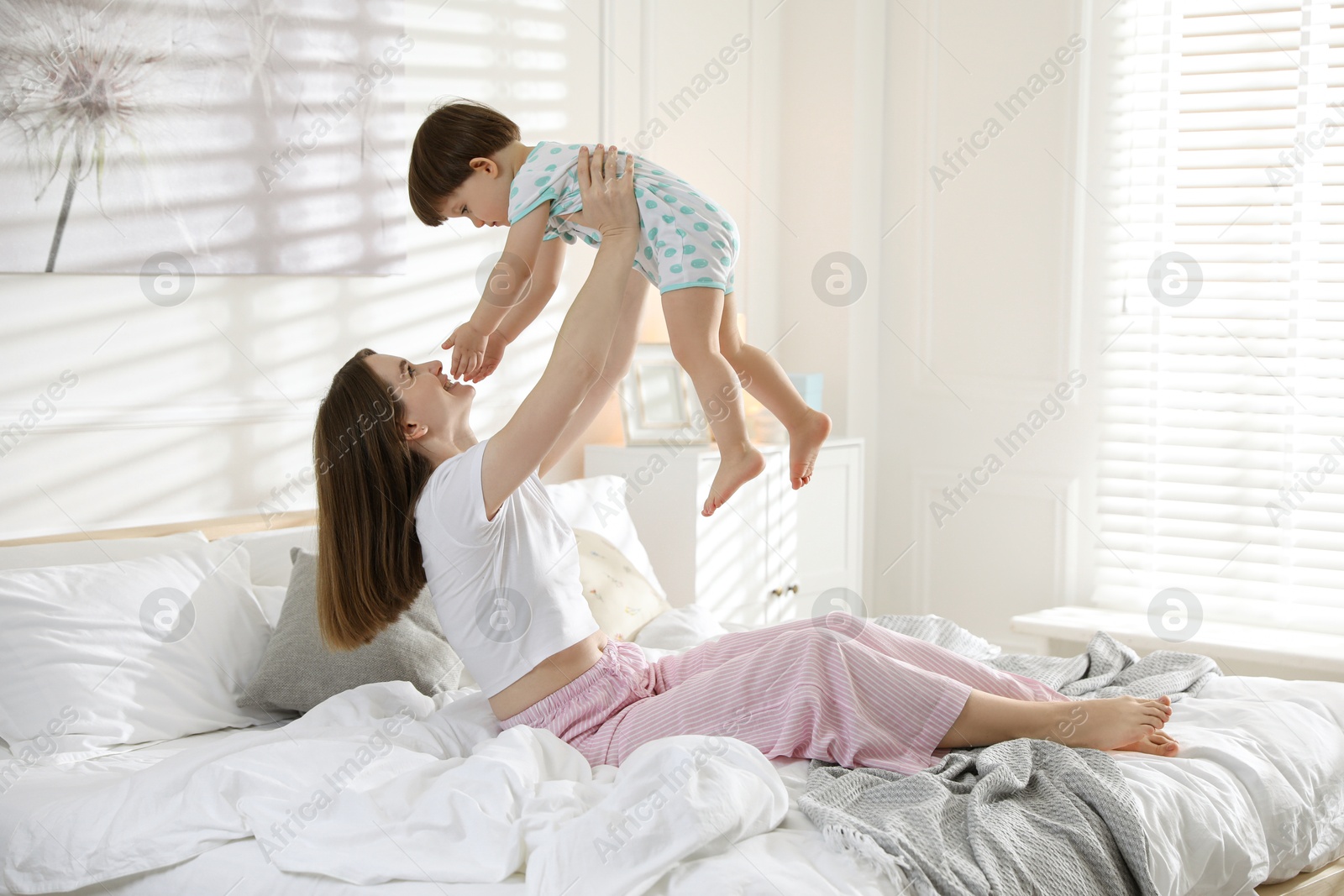 Photo of Happy mother playing with her little son in bedroom