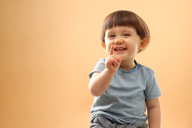 Photo of Portrait of smiling little boy on beige background. Space for text