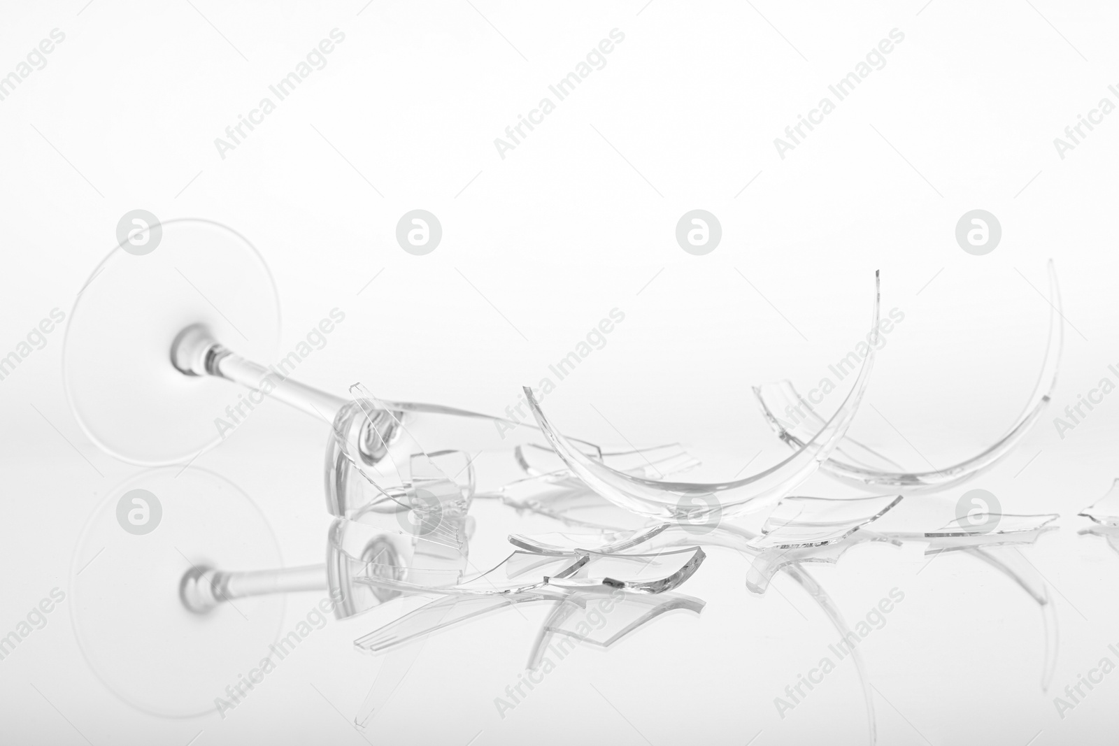 Photo of Pieces of broken wine glass on white background