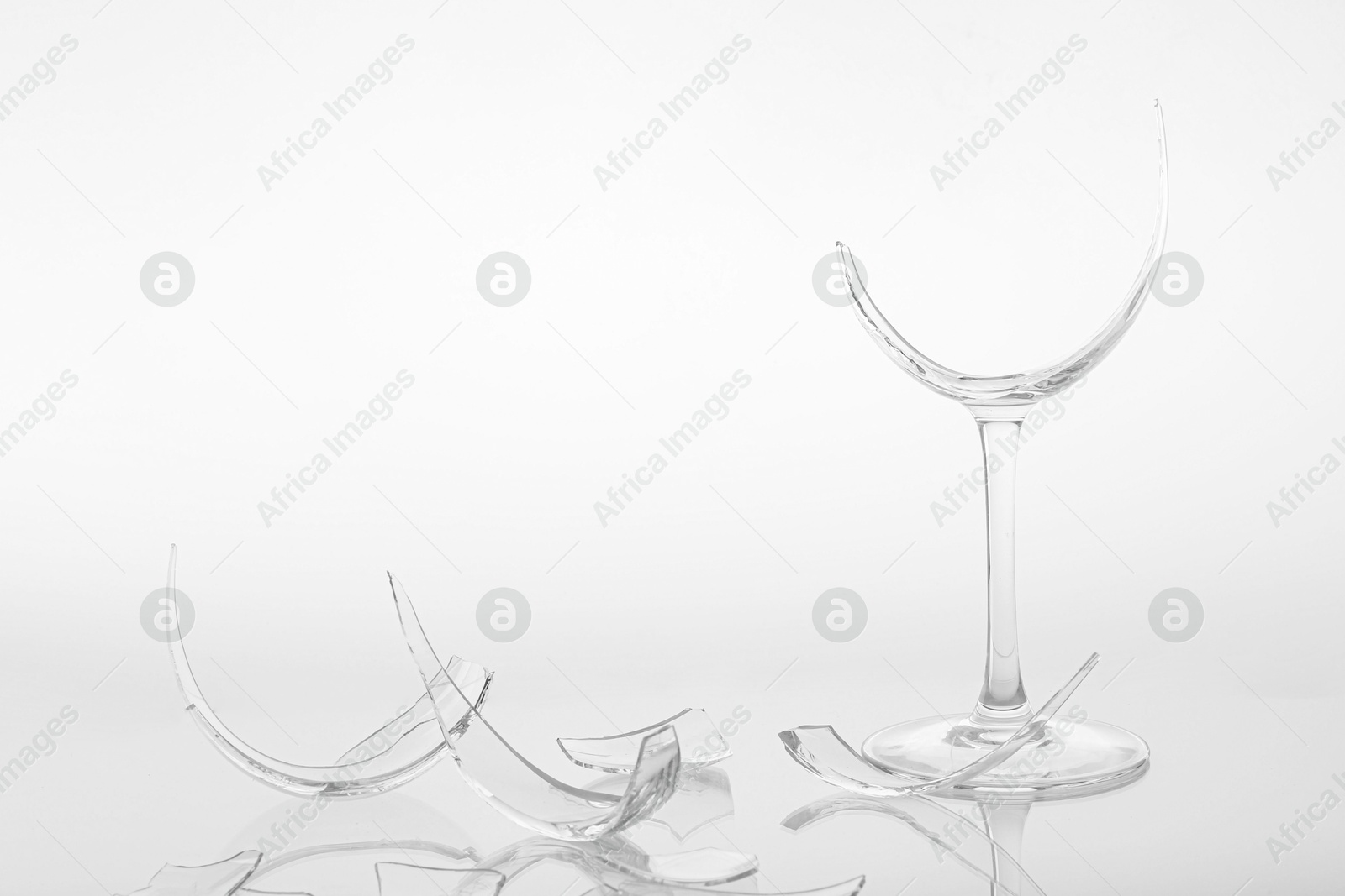 Photo of Pieces of broken wine glass on white background