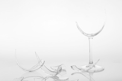 Photo of Pieces of broken wine glass on white background