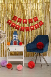 Photo of Bright pinata in shape of rocket and party accessories in festive decorated room