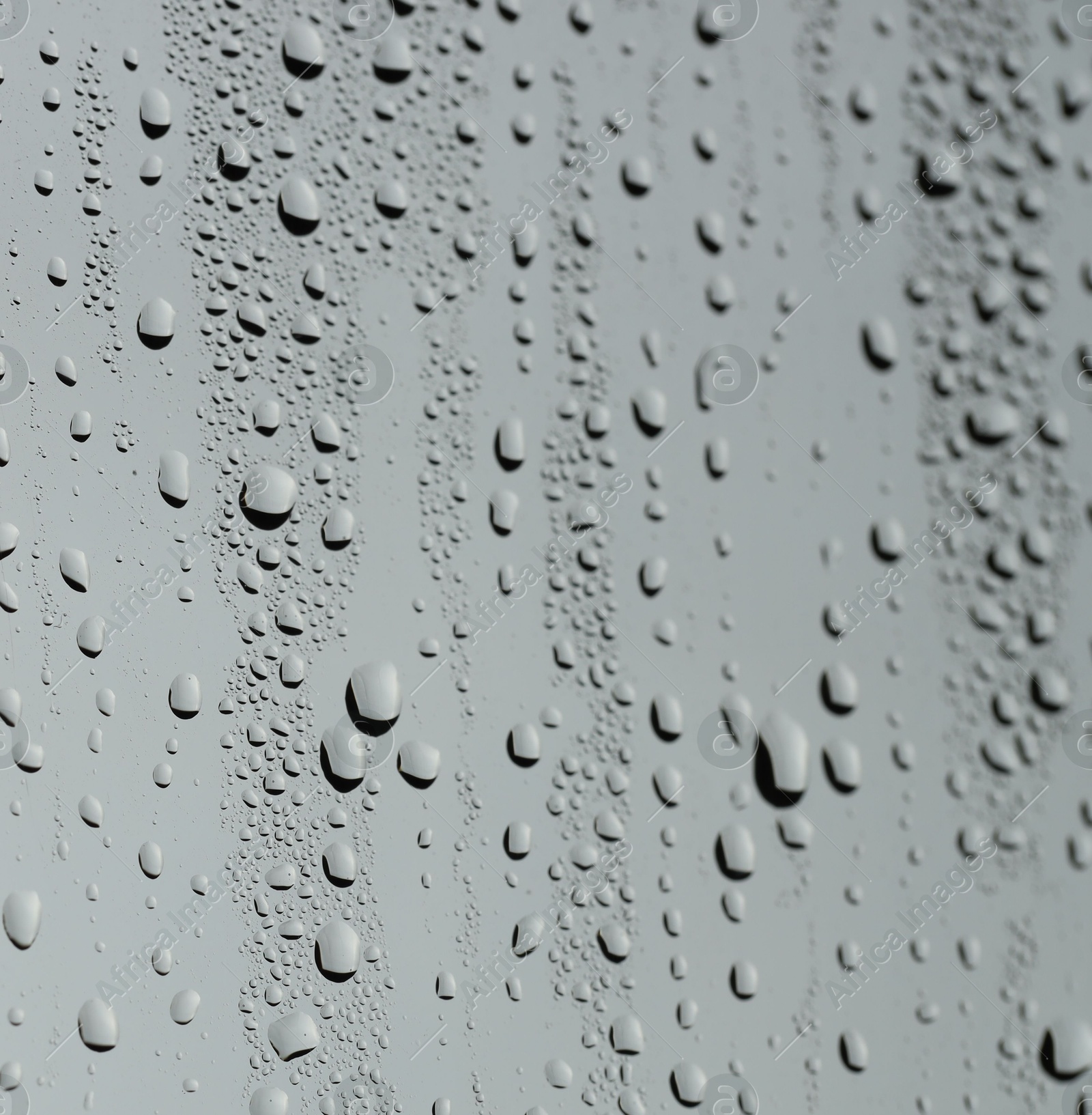 Photo of Water drops on grey glass surface, closeup