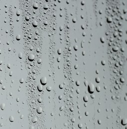 Photo of Water drops on grey glass surface, closeup