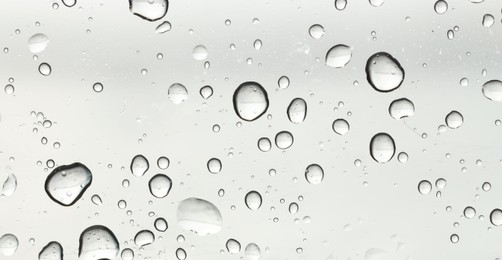 Photo of Water drops on light grey glass surface, top view