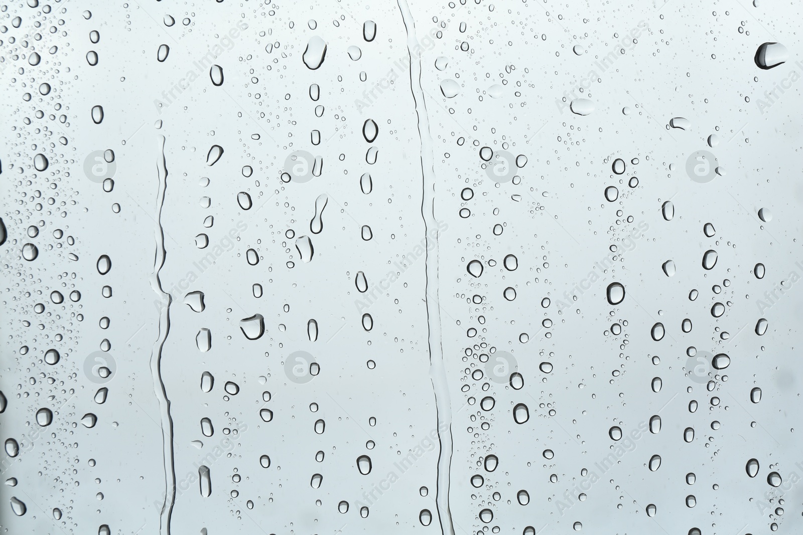 Photo of Many water drops on light glass surface, closeup