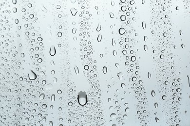 Photo of Many water drops on light glass surface, closeup