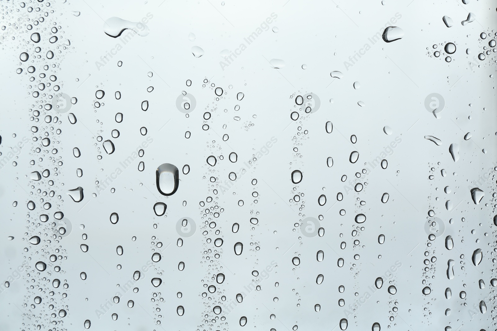 Photo of Many water drops on light glass surface, closeup