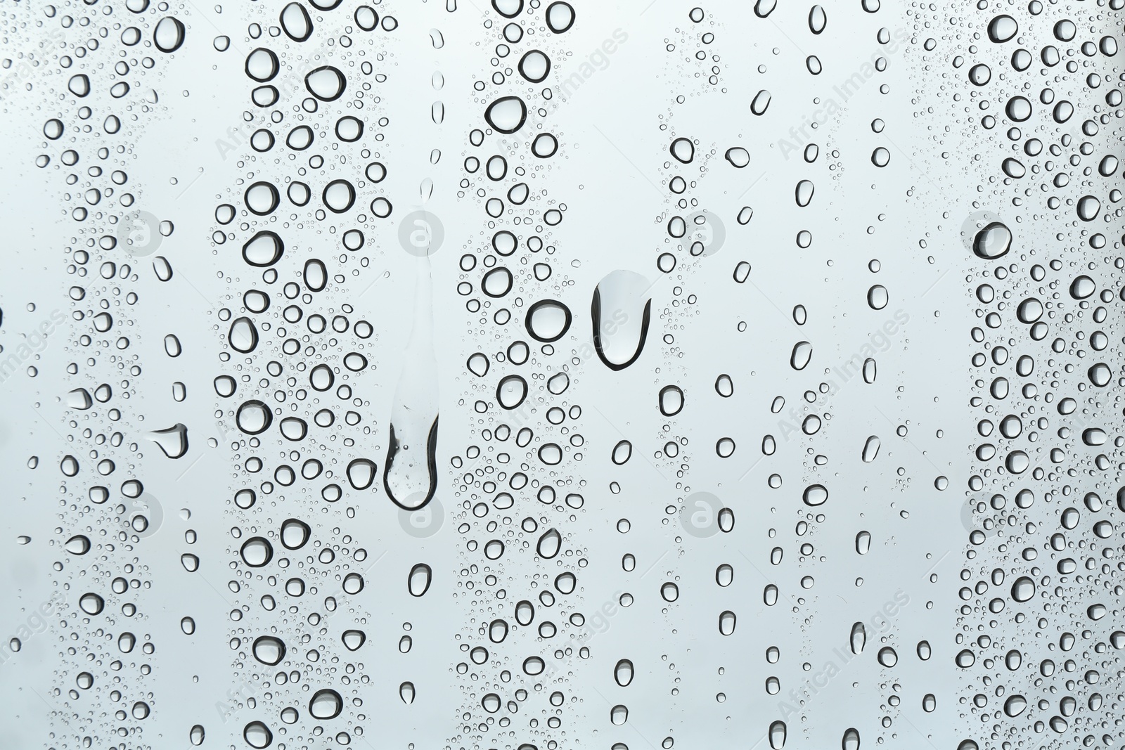 Photo of Many water drops on light glass surface, closeup