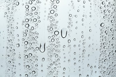 Many water drops on light glass surface, closeup