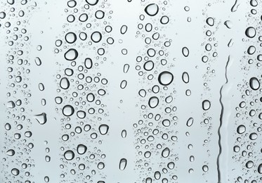 Photo of Many water drops on light glass surface, closeup