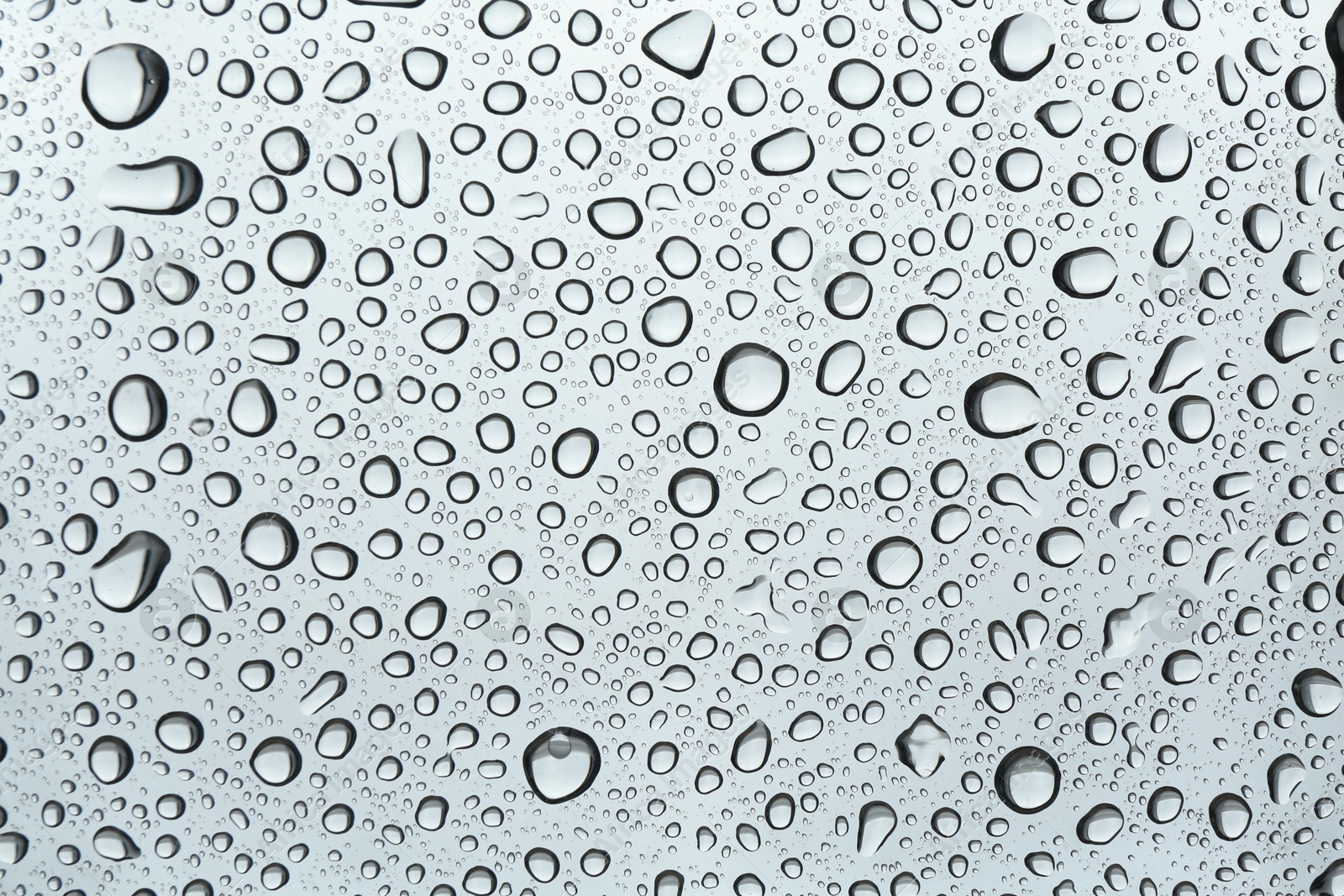 Photo of Many water drops on light glass surface, closeup