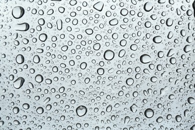 Many water drops on light glass surface, closeup