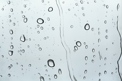 Photo of Many water drops on light glass surface, closeup