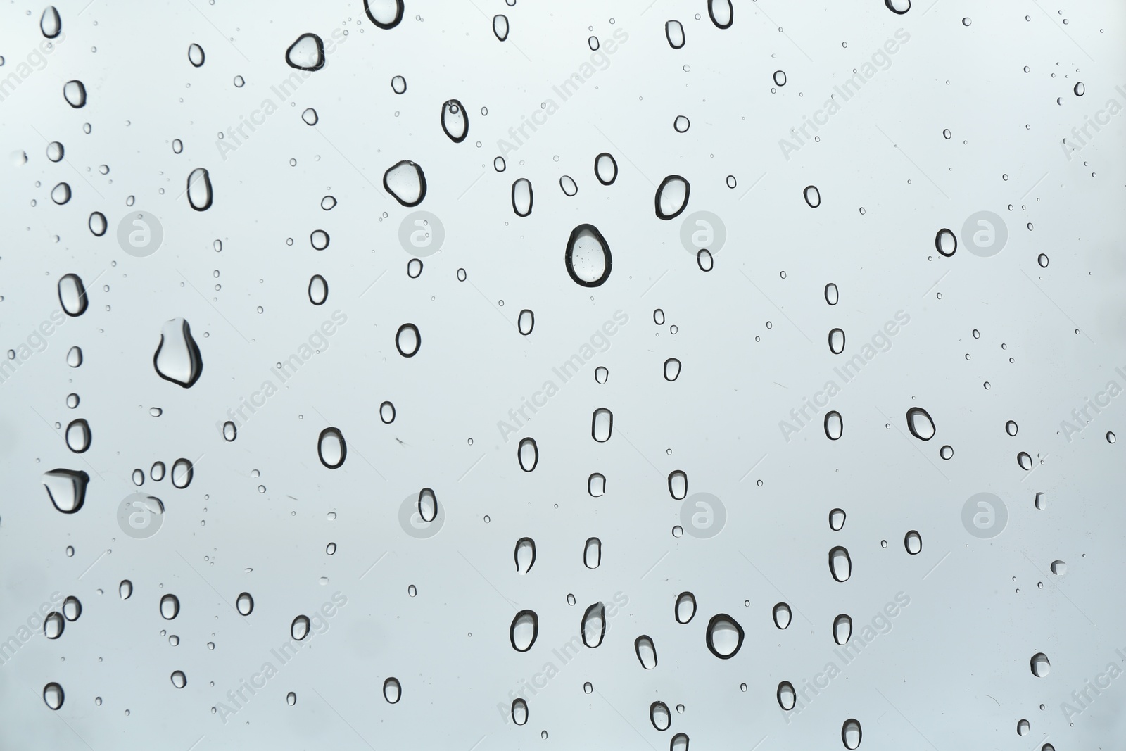 Photo of Many water drops on light glass surface, closeup