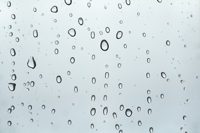 Photo of Many water drops on light glass surface, closeup