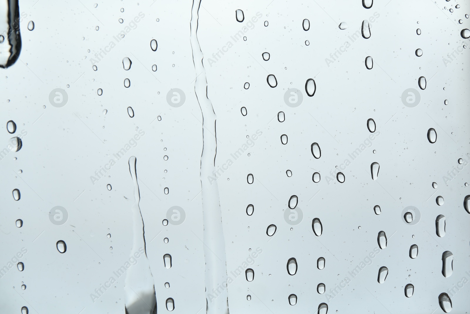 Photo of Many water drops on light glass surface, closeup