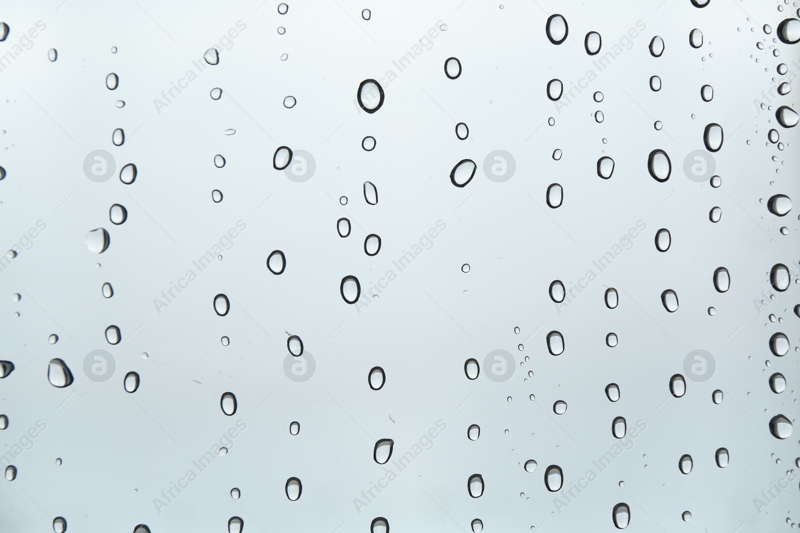 Photo of Many water drops on light glass surface, closeup