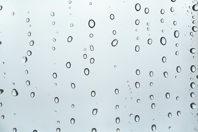 Photo of Many water drops on light glass surface, closeup