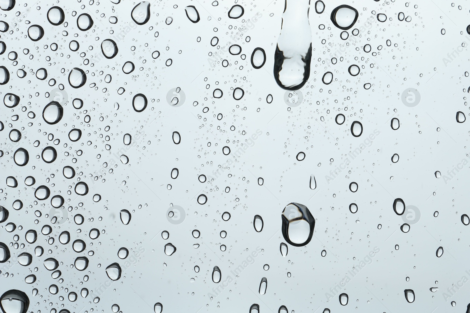 Photo of Many water drops on light glass surface, closeup