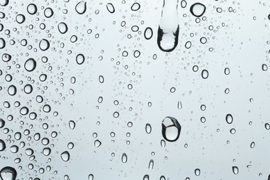 Photo of Many water drops on light glass surface, closeup